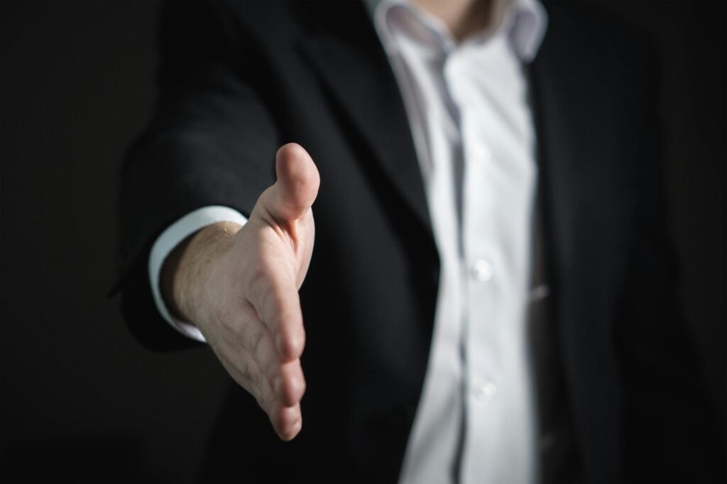pexels-photo-327540-327540 Close-up of a businessman extending hand for a handshake, symbolizing agreement and partnership.