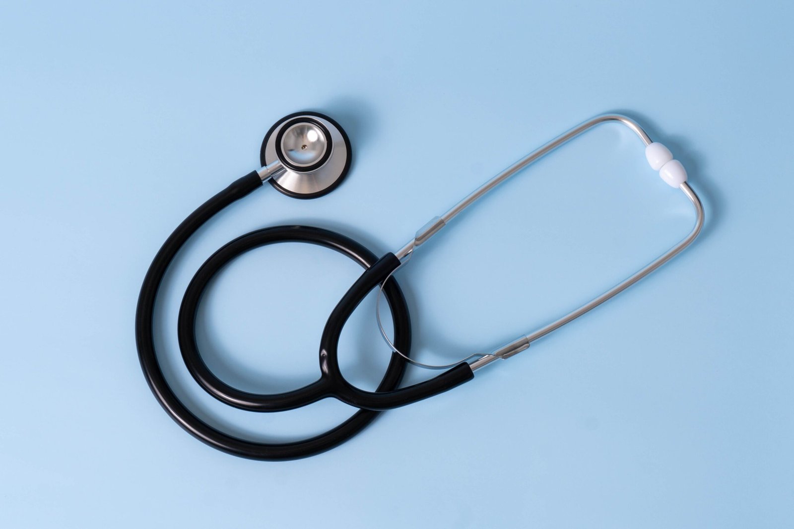 Medical stethoscope placed on a light blue surface, symbolizing healthcare and medical examination.
