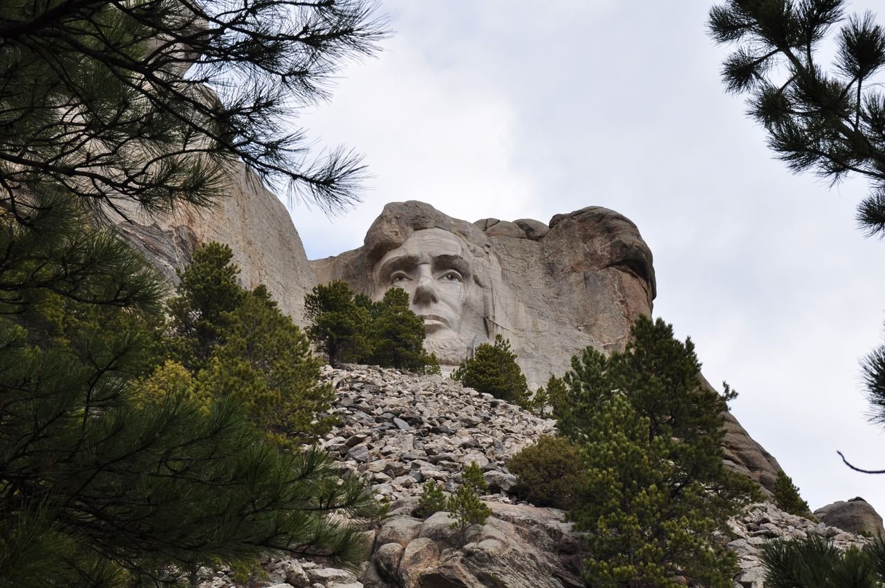 Dramatic view of Abraham Lincoln at Mount Rushmore surrounded by nature.